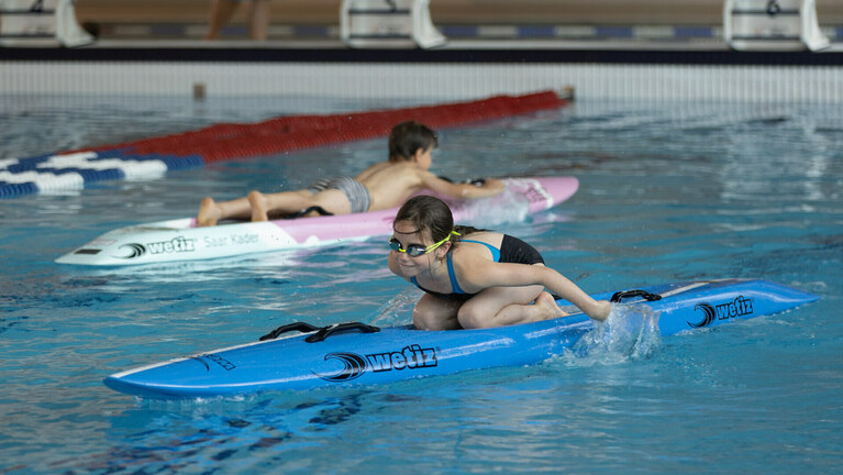 Kinder auf einem Stand-Up-Paddle-Board in der Schwimmhalle