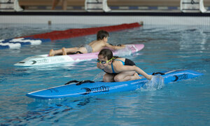 Kinder auf einem Stand-Up-Paddle-Board in der Schwimmhalle