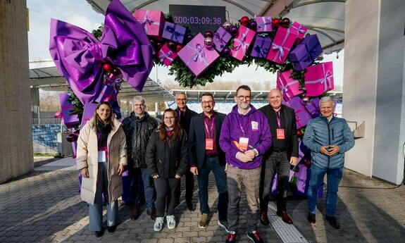 Gruppenfoto vor einem Herz-Motiv mit einem Countdown-Zähler