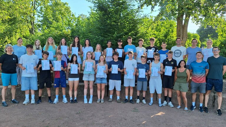 Schülergruppe auf dem Schulhof zeigt ihre Urkunden.
