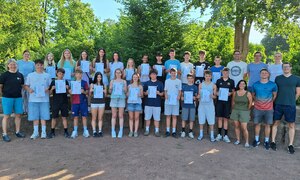 Schülergruppe auf dem Schulhof zeigt ihre Urkunden.